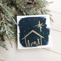 a christmas ornament with a nativity scene painted on it next to evergreen branches