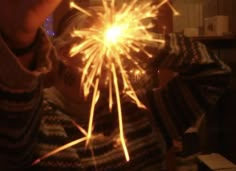 a person holding a sparkler up to their face in front of the camera with both hands