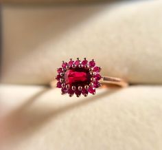 a ring with a red stone surrounded by pink stones