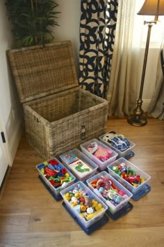 an open trunk sitting on top of a hard wood floor next to toy boxes filled with legos