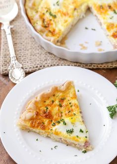 a slice of quiche on a white plate with a serving spoon next to it