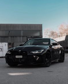 a black bmw car parked in front of a building with no doors on it's side