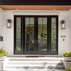 two potted plants are sitting on the front step of a house with double doors