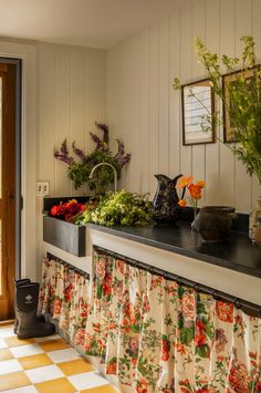 a kitchen counter topped with lots of flowers next to a window covered in valance