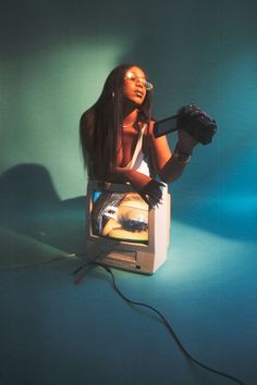 a woman sitting on top of a tv in front of a green wall