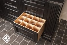 an open drawer in the middle of a kitchen with black cabinets and grey tile flooring