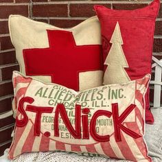 two red and white pillows sitting on top of a bed next to a brick wall