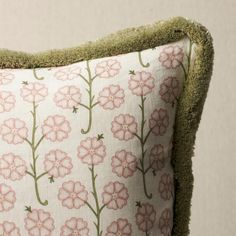 a pink flowered pillow with green trim on it's sides and a white background