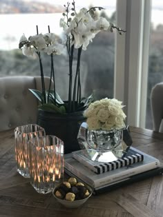 a table with flowers and candles on top of it next to a book, glass vase filled with flowers