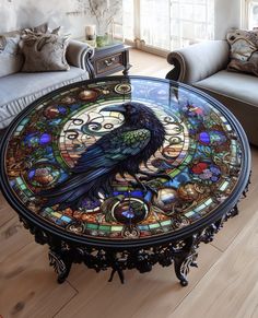 a glass table with a black bird painted on it's side and ornate details around the top