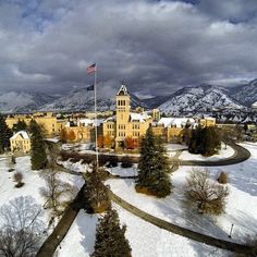 an aerial view of a large building with snow on the ground and mountains in the background