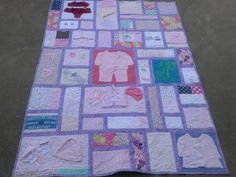 a quilted blanket with baby clothes on it