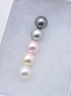 three different colored pearls in a white box