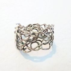 Discover the enchanting allure of this Artisan Crafted Sterling Silver Freeform Band Style Ring. Expertly fashioned in sterling silver, this unique piece showcases an intricate intertwining design of various wires, creating a captivating vine-like aesthetic. The freeform nature of the ring adds a touch of organic elegance, making it a truly one-of-a-kind accessory. Though it bears no official markings, it has been thoroughly tested and confirmed to be genuine sterling silver. This exquisite ring measures a size 6 1/2, perfect for adding a subtle yet sophisticated statement to any outfit. Embrace the beauty of handcrafted artistry with this timeless sterling silver creation. Modern Twist Silver Wire Wrapped Jewelry, Silver Spiral Wire Wrapped Rings, Silver Filigree Metal Ring, Elegant Metal Wire Wrapped Rings, Elegant Wire Wrapped Metal Rings, Unique Adjustable Silver Filigree Ring, Silver Metal Fusion Rings, Silver Wire Wrapped Metal Rings, Silver Fusion Style Metal Rings