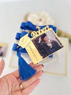 a person holding a blue and gold graduation ornament with a photo on it