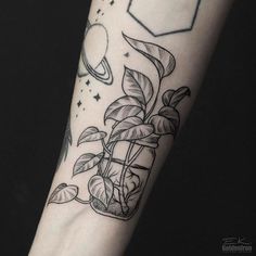 a black and white photo of a tattoo on someone's arm that has a plant growing out of it