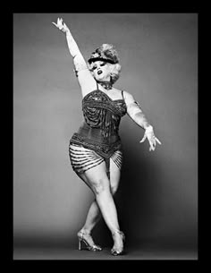 a black and white photo of a woman in an old fashion dress with her arms outstretched