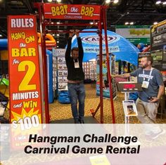 the hangman challenge carnival game rental booth is set up with two men standing in front of it