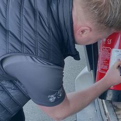 a man is looking at something on the side of a red fire extinguisher