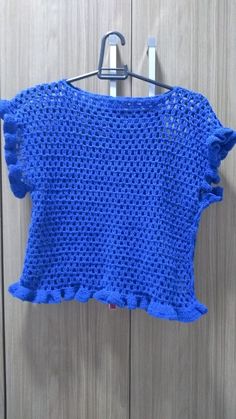 a blue crocheted top hanging on a clothes rack