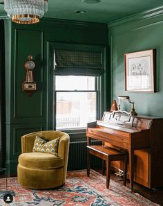 a living room with green walls and a piano in the corner next to a chair