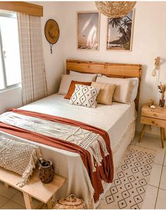 a bed sitting in a bedroom next to a window with pictures on the wall above it