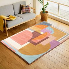 a living room filled with furniture and a rug on top of a hard wood floor