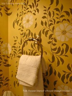 a towel rack in the corner of a bathroom next to a wall with flowers on it