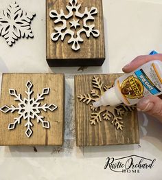 someone is painting snowflakes on wooden blocks