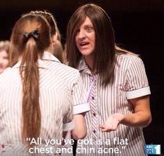 a woman with long hair talking to another woman who is wearing a striped shirt and has her hand on her hip