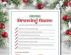 a christmas drawing game is shown on a white table with ornaments and red balls around it