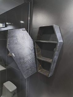 a bathroom with black walls and a metal object on the wall next to the toilet