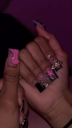 two hands with pink and black nail polish holding each other