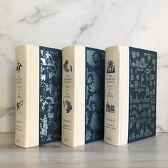 three books sitting on top of a wooden table next to a white marble countertop