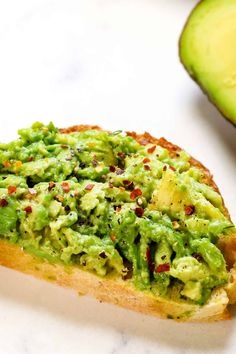 a piece of bread with guacamole on it next to an avocado