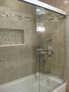 a glass shower door in a bathroom with tile walls and flooring on the wall