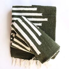 three green and white towels folded on top of each other with fringes around them