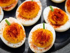 deviled eggs on a black plate topped with chili