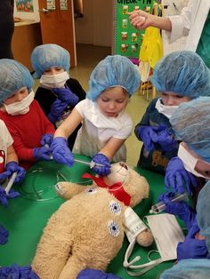 a group of children wearing surgical garb around a teddy bear