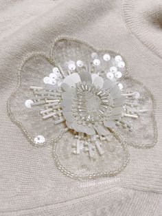 a white flower brooch sitting on top of a sweater