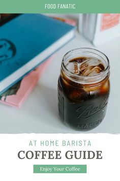 a mason jar filled with coffee sitting on top of a table next to a book