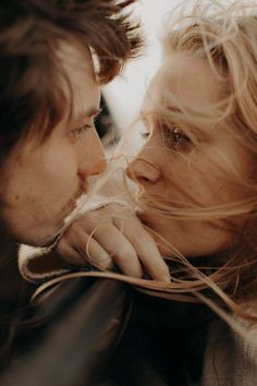 a man and woman kissing each other with long hair blowing in front of their faces