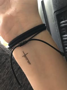 a woman's arm with a cross tattoo on the left side of her wrist