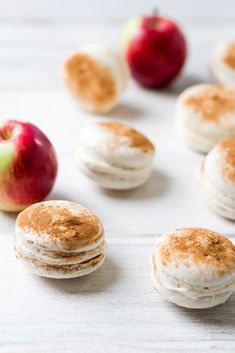 several small macaroni and cheeses with an apple in the background on a white surface