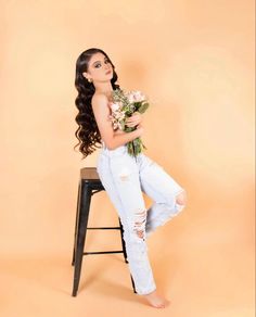 a woman sitting on a stool holding flowers