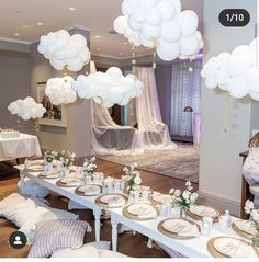 a table set up for a party with white balloons