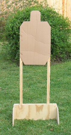 a cardboard sign sitting on top of a grass covered field in front of a wooden fence