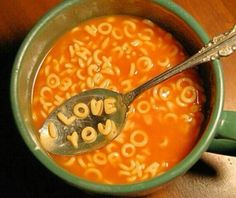 a spoon with the word love you written on it in a bowl filled with soup