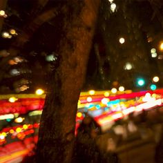 blurry image of city lights at night with trees and buildings in the foreground