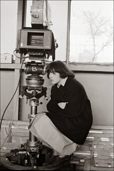 black and white photograph of a woman looking through a microscope